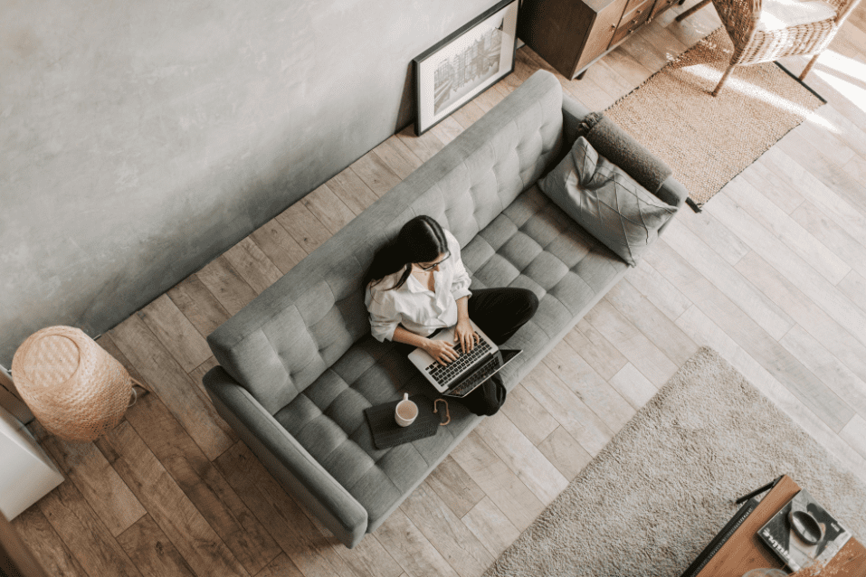 A person sitting on top of a couch with a laptop.