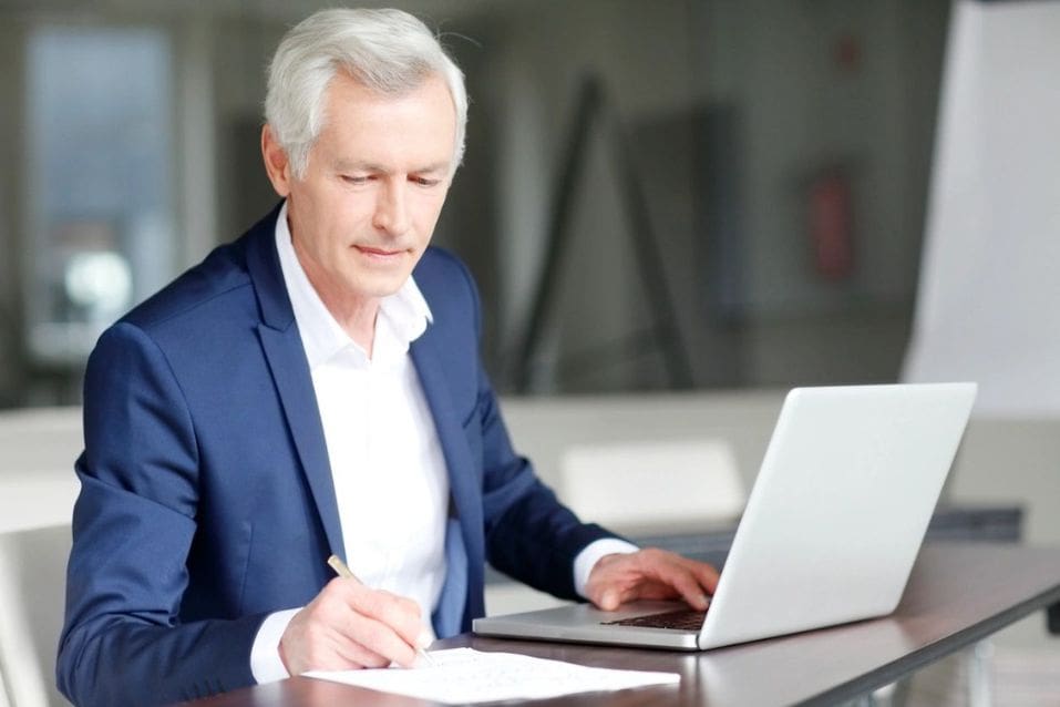 A man in a suit is looking at his laptop